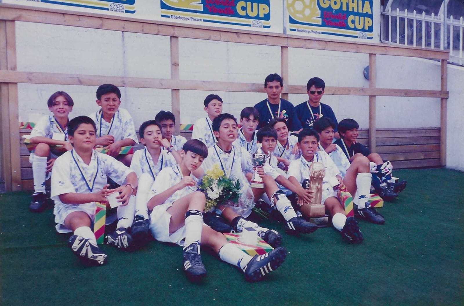 Archivo: equipo guatemalteco con medallas, flores y trofeos frente a los carteles de la Gothia Cup en los años noventa.